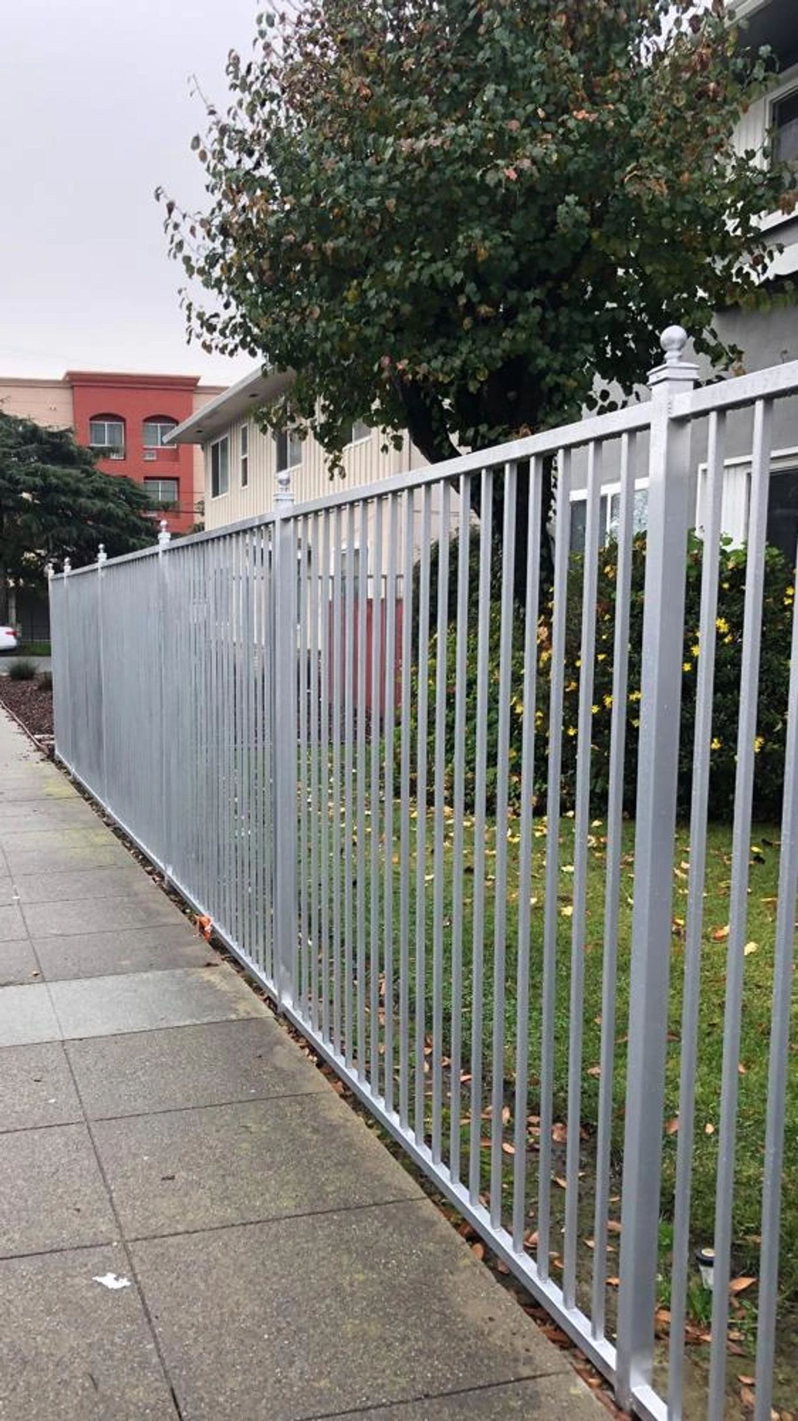 A galvanized picket perimeter fence along a sidewalk, an ATR Welding installation